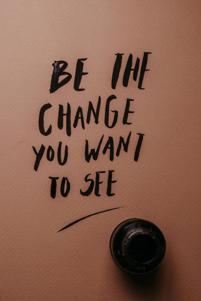 pexels-photo-6185624-6185624 Inspirational message 'Be the change you want to see' in black ink on pink surface.